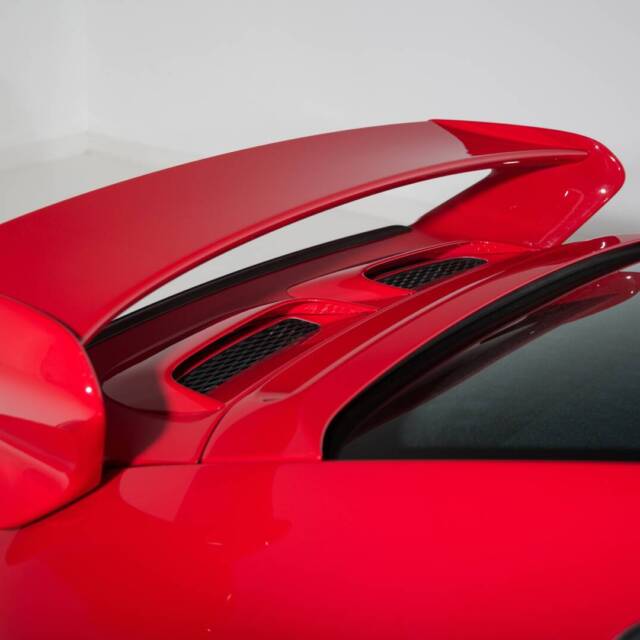The spoiler of a red sports car in a white room
